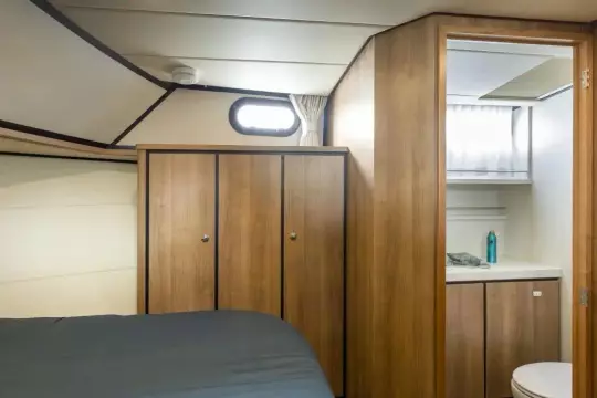 Interior of 2025 Linssen 45 SL Sedan yacht, featuring wood cabinetry and compact bathroom.