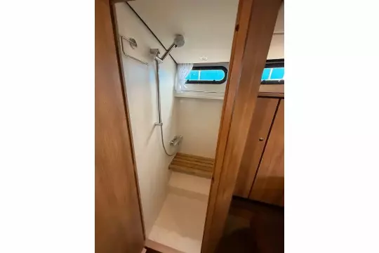 Shower area in 2025 Linssen 45 SL Sedan yacht with wooden accents and window.