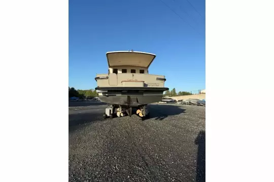 2025 Linssen 45 SL Sedan yacht on gravel lot, rear view under clear blue sky.