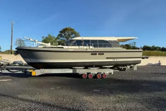 2025 Linssen 45 SL Sedan yacht on trailer, parked outdoors under clear blue sky.