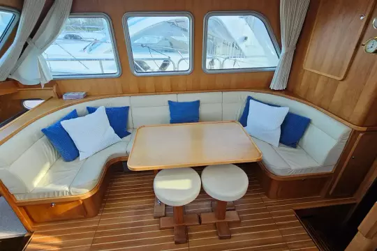 Cozy interior of 2008 Linssen Grand Sturdy 380 AC with cushioned seating and wooden table.