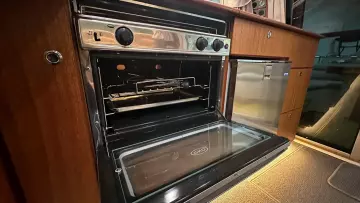 Open oven in a 2008 Nimbus 42 Nova yacht kitchen with wooden cabinetry.