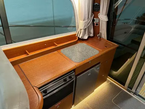 Compact kitchen area in a 2008 Nimbus 42 Nova boat, featuring wood cabinetry and modern appliances.