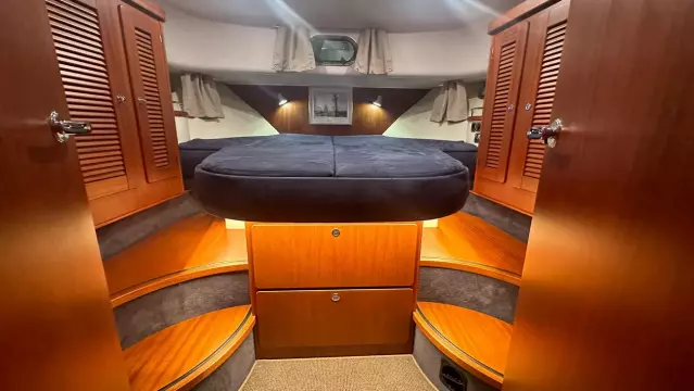 Luxurious cabin interior of 2008 Nimbus 42 Nova yacht with wooden finishes and cozy bedding.