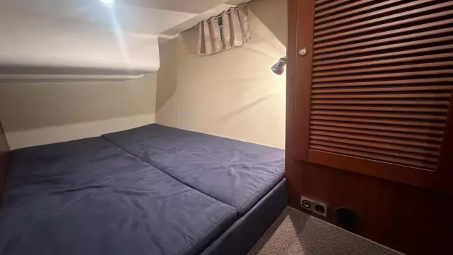 Cozy cabin interior of 2008 Nimbus 42 Nova with blue bedding and wooden accents.